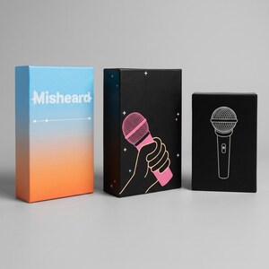 May include: Three boxes with microphone designs. The box on the left has a gradient of blue to orange with the word "Misheard" and a sound bar graphic. The middle box is black with a pink microphone graphic. The box on the right is black with a white microphone graphic.