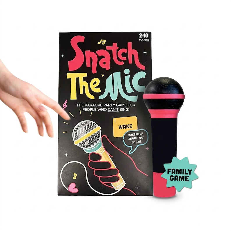 May include: A karaoke party game called "Snatch The Mic" with a black, red, and yellow design. The game includes a microphone prop and a green star-shaped "Family Game" emblem. The text reads "The Karaoke Party Game for People Who Can't Sing!"