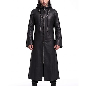 May include: A black full-length hooded coat featuring a front zipper closure, long sleeves, and a decorative silver-toned metal chain detail attached to the neckline. The garment has a structured fit with vertical seam detailing along the front.
