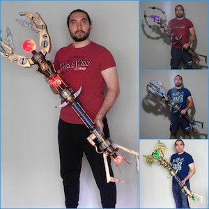 Könnte beinhalten: Ein detaillierter Stab im Steampunk-Stil mit einem komplexen Design. Der Stab weist eine Kombination aus Metallfarben auf, darunter Gold, Kupfer und Silber, mit roten und blauen Akzenten. Er hat eine große, leuchtende rote Kugel an der Spitze und komplizierte mechanische Details.