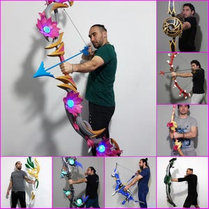 May include: A selection of fantasy bows in different styles. One bow has a pink and gold floral design with blue details and a blue arrow. Other bows feature red, gold, and blue colour schemes. The bows are held by a person.