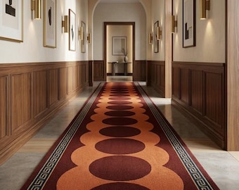 May include: A long runner rug featuring a repeating pattern of large dark red circles centered on a vibrant orange background, bordered by a classic Greek key design in dark blue and gold, laid out in a hallway with wood paneled walls.