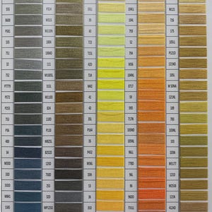May include: A color chart displaying a wide array of thread colors, arranged in columns and rows. Each color is represented by a swatch with a corresponding number and code, ranging from greens and blues to yellows and oranges. Ideal for embroidery and sewing projects.