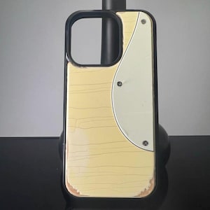 May include: A phone case with a black frame and a light wood grain design. A white, semi-circular accent is attached with three silver screws. The case has a distressed, vintage appearance.