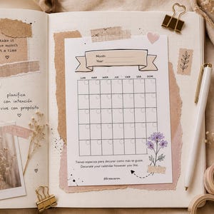 Puede incluir: Un diario abierto con una hoja de calendario mensual que incluye un banner para mes y año, cuadrícula y flores. La página presenta trozos de papel kraft rasgado, un bolígrafo blanco, clips dorados y texto en español e inglés.
