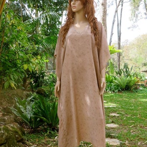 May include: A long, flowing, brown kaftan with a V-neck and a subtle floral pattern. The kaftan is worn by a mannequin in a garden setting.