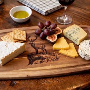 Peut inclure: Un plateau de service en bois avec différents fromages, des crackers, des raisins et des figues. Le plateau est orné d'une silhouette de cerf. Un petit bol d'huile d'olive et un verre de vin rouge complètent la présentation rustique et gastronomique.
