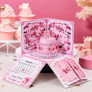 May include: A pink pop-up birthday card with a miniature cake and the number 5 on top. The card features floral and butterfly designs, with an October calendar and the words "Happy Birthday!" visible.