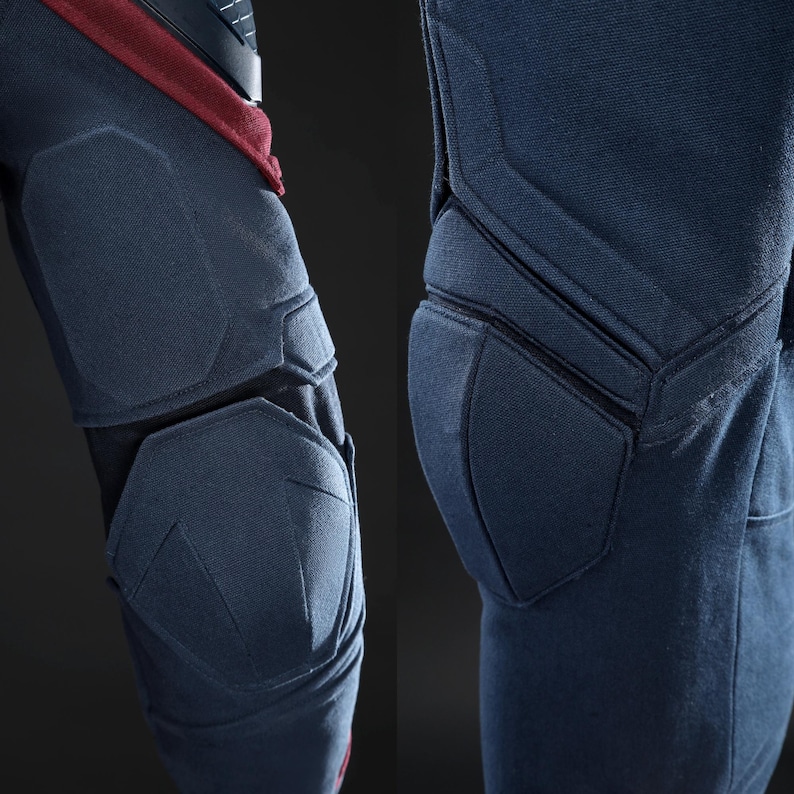 May include: Close-up of navy blue protective gear, possibly for sports or tactical use. The gear features padded sections with geometric stitching, offering enhanced protection. The design incorporates a combination of navy blue and black materials.