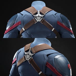 May include: Detailed view of a blue costume featuring brown straps and silver metalwork. The costume has red detailing and textured shoulder pads. The design is reminiscent of a superhero outfit.