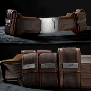 May include: A brown utility belt with multiple pouches and a large, silver buckle. The belt is made from a combination of leather and woven fabric, with metal accents on the pouches and buckle. The design is detailed and appears to be a costume accessory.