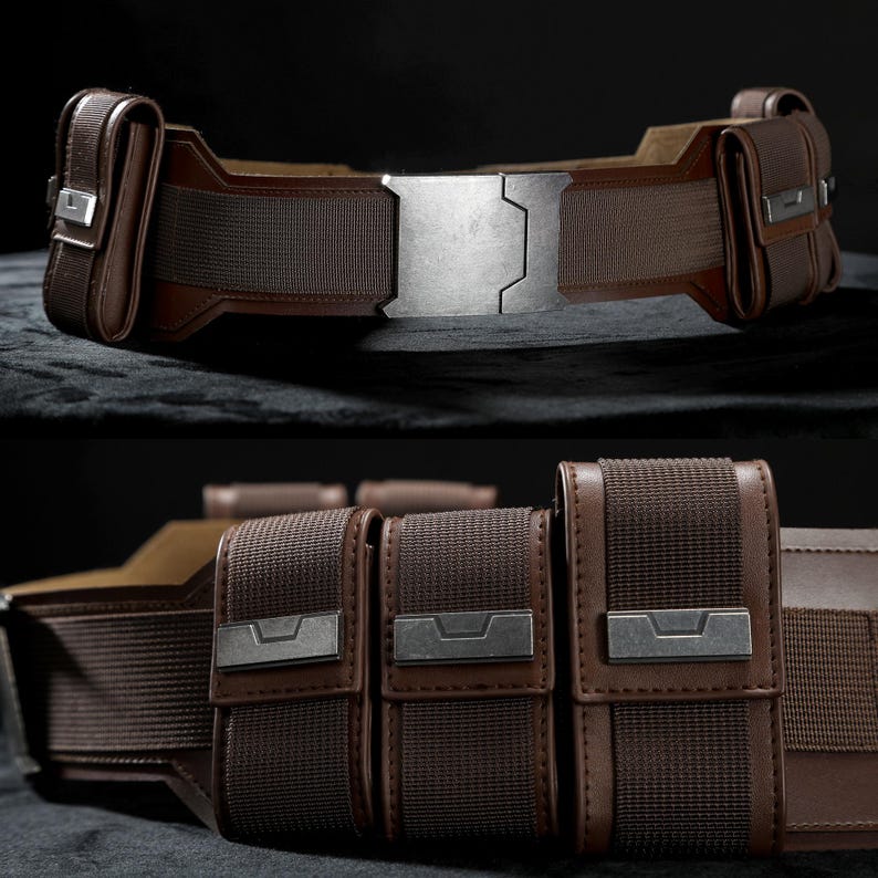 May include: A brown utility belt with multiple pouches and a large, silver buckle. The belt is made from a combination of leather and woven fabric, with metal accents on the pouches and buckle. The design is detailed and appears to be a costume accessory.