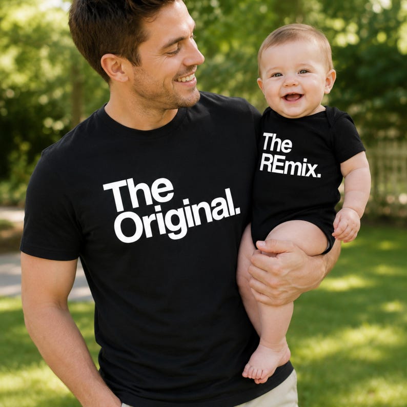 May include: A black short-sleeved t-shirt with the white text The Original. and a matching black short-sleeved baby bodysuit with the white text The REmix. The text is printed in a bold, sans-serif font on the front of each garment.