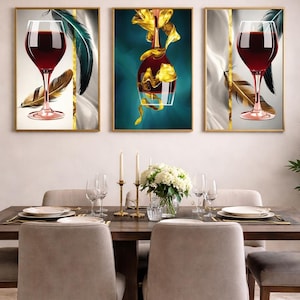Peut inclure: Trois tableaux encadrés représentant des verres à vin et une bouteille de vin avec des accents dorés. L'œuvre comprend des plumes et des fonds abstraits. La table à manger est dressée avec des assiettes, des verres et des bougies.