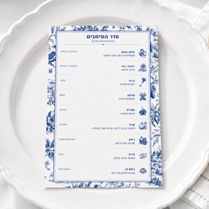 May include: A rectangular Rosh Hashanah Seder Simanim card featuring blue and white toile-style botanical illustrations. The card lists traditional foods in English and Hebrew, including apple, honey, carrot, leek, beet, dates, gourd, pomegranate, and fish.