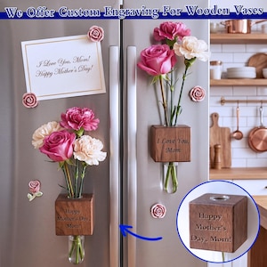May include: Wooden vases with custom engraving, holding pink and white flowers, are displayed on a refrigerator. The vases are engraved with "I Love You, Mom!" and "Happy Mother's Day, Mom!" Decorative rose magnets and a Mother's Day card are also visible.