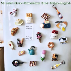 May include: A selection of 3D food-themed fridge magnets. The magnets depict various food items such as a croissant, ice cream, coffee, and bread. Text on the magnets includes "BREAD", "Pain", "TOMATO", and "You are beautiful".