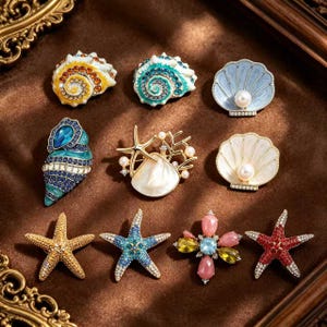 Puede incluir: Una colección de nueve broches con temática oceánica que presentan varios diseños, incluyendo caracoles en espiral, almejas con perlas, estrellas de mar y una pieza en forma de flor, decorados con pedrería, esmalte y perlas.