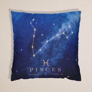 Könnte beinhalten: Ein quadratisches Dekokissen mit einem tiefblauen Galaxie-Druck und einer weißen Sternbildkarte des Tierkreiszeichens Fische. Das Design zeigt das Fische-Symbol, das Wort PISCES und den Text FEBRUARY 19 - MARCH 20 in einer hellen, eleganten Schrift.