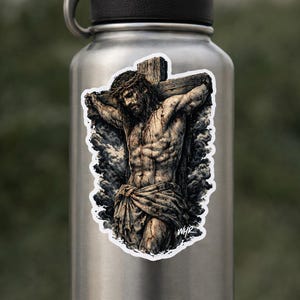Puede incluir: Una pegatina con una ilustraci&oacute;n detallada de Jesucristo en la cruz. La obra de arte representa una figura musculosa con una corona de espinas, envuelta en tela, sobre un fondo de nubes oscuras. La pegatina est&aacute; adherida a una botella de agua plateada.