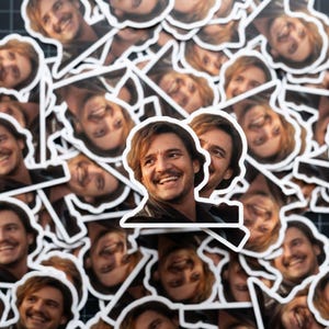 May include: A collection of white-bordered stickers featuring a smiling man with brown hair and a dark jacket. The stickers are scattered across a black surface, creating a pattern of repeated images.