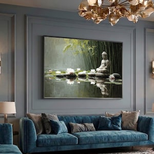 Op de afbeelding: Een rechthoekige wandkunstprint met een stenen Boeddhabeeld dat mediterend op een rots zit in een vijver met witte waterlelies en groene bamboestengels op de achtergrond, met zachte verlichting en reflecties op het wateroppervlak.