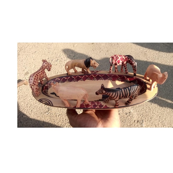 Hand-carved by Kenyan craftspeople, this wooden bowl features safari wildlife in relief — functional art with a real cultural provenance story, not a factory knockoff.