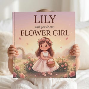 May include: A square hardcover book with a pastel sunset background featuring a cartoon illustration of a child in a white dress and floral crown holding a basket of petals. The text reads LILY will you be our FLOWER GIRL in dark brown font.