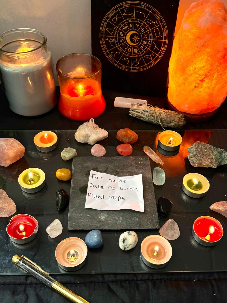 May include: A square slate tile with a white paper note reading Full name, Date of birth, Ritual type, surrounded by various crystals, tea light candles in red, orange, and green, a sage bundle, a salt lamp, and a gold pen on a glass surface.