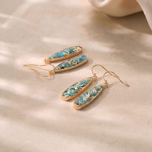 Peut inclure: Boucles d'oreilles pendantes dor&eacute;es avec des pierres en forme de goutte d'eau, turquoise et mouchet&eacute;es d'or. Les boucles d'oreilles ont une fermeture &agrave; crochet simple. Bijoux pour un usage quotidien ou des occasions sp&eacute;ciales.