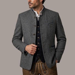 May include: A grey wool jacket with a mandarin collar, dark blue trim, and wooden buttons. The jacket is worn over a dark blue waistcoat and a white collared shirt. The outfit is completed with brown leather trousers.