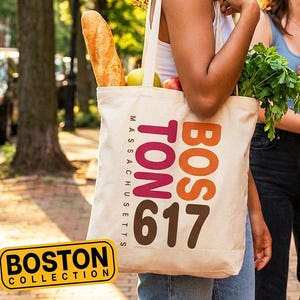 May include: A group of three smiling people walking on a brick-paved street. One person carries a canvas tote bag with "BOSTON" and "617" printed on it, filled with groceries. The bag also has the text "MASSACHUSETTS" printed on it. The text "If you don't know, ask your Nana..." is at the top.