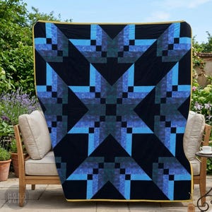 May include: A large, square quilt with a geometric star pattern in shades of blue and teal on a black background. The quilt is draped over a wooden chair on a patio. The edges are trimmed with a gold border. The brand name "MONA VONA" is visible.