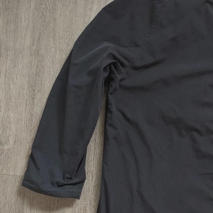 May include: A solid black long-sleeve shirt featuring a smooth, matte fabric texture. The garment has a simple, clean design with a standard sleeve construction and a straight hemline, showcasing a plain and uniform dark colour throughout the piece.