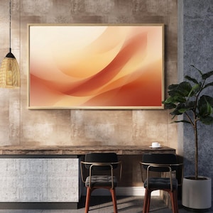 Könnte beinhalten: Abstrakter Kunstdruck in einem Holzrahmen. Das Kunstwerk zeigt fließende, geschichtete Formen in Orange-, Rot- und Cremetönen. Der Druck hängt über einem Holztisch mit zwei schwarzen Stühlen und einer Topfpflanze.