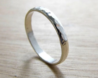 May include: A silver hammered band ring. The ring is simple and has a smooth, polished finish.