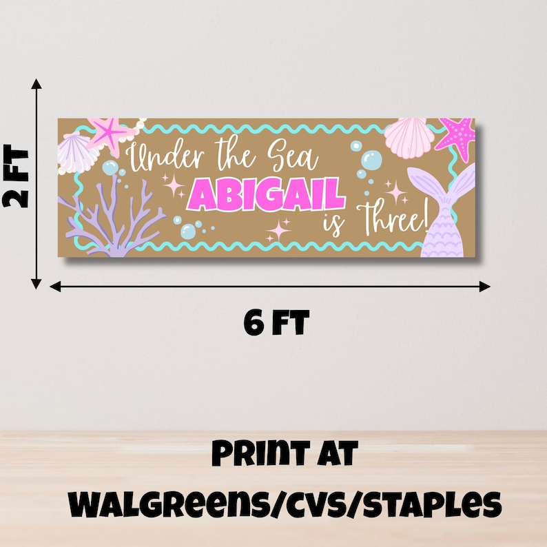 May include: A rectangular banner measuring 0.6 metres by 1.8 metres with a tan background, featuring the text Under the Sea ABIGAIL is Three! in pink and white. The design includes illustrations of pink starfish, seashells, coral, and bubbles.