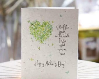May include: A Mother's Day card featuring a heart made of green leaves and the message "Of all the moms in the world, I'm so glad you're mine. Happy Mother's Day!" on a light-toned card.