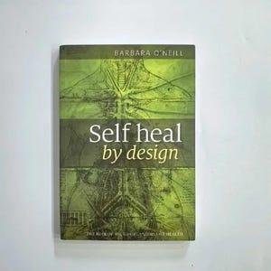 Puede incluir: Un libro titulado "Self heal by design" de Barbara O'Neill. La portada es predominantemente verde con una ilustración anatómica estilizada. El texto es en blanco, con el subtítulo "The Role of Micro-Organisms for Health."
