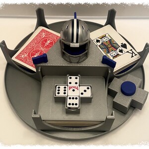 Op de afbeelding: Een ronde grijze spelorganizer van kunststof met een footballhelm in het midden, twee vakken voor speelkaarten en een kruisvormige houder met vijf witte dobbelstenen met zwarte stippen en het rode Bicycle-logo op de middelste dobbelsteen.