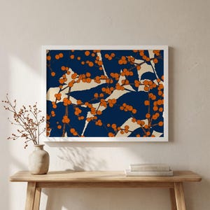 Puede incluir: Una impresión artística enmarcada con un diseño botánico. La obra de arte presenta un fondo azul marino con formas abstractas color crema y racimos de bayas naranjas. La impresión se muestra en un marco blanco, añadiendo una estética limpia y moderna.