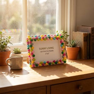 May include: A rectangular photo frame decorated with a border of multicolored beads in shades of pink, yellow, blue, green, and silver. The center insert features the text SUNNY LIVING - DIY PHOTO FRAME 4"x6" printed in black on a white background.