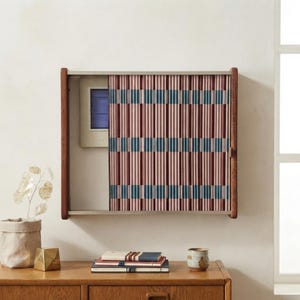 May include: A rectangular wall-mounted cabinet with a dark wood frame and a sliding tambour door featuring a vertical ribbed pattern in alternating shades of dusty pink and dark teal. The door is partially open, revealing a light interior panel.