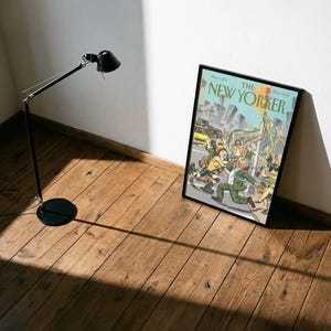 May include: A framed magazine cover titled The New Yorker dated May 2, 1994, featuring a colorful illustration of people dancing around a maypole in a city street with skyscrapers in the background, enclosed in a simple black frame.