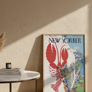 May include: A framed vintage New Yorker magazine cover with a red lobster illustration. The cover art shows a man painting a building with a seagull. The magazine is dated March 22, 1958.