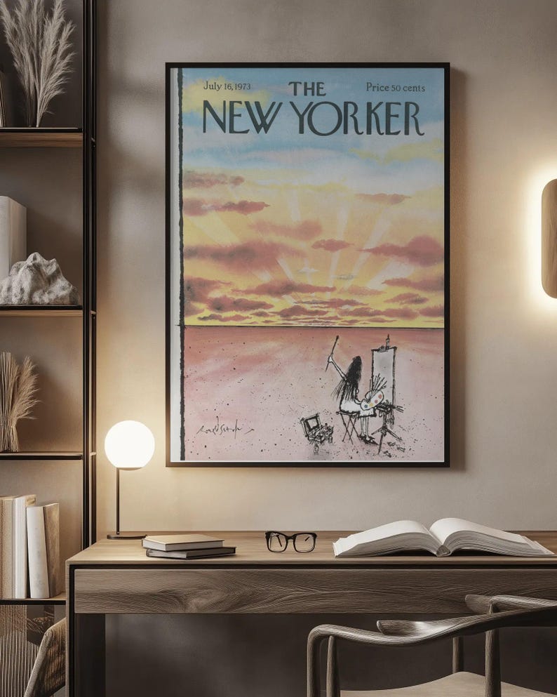 May include: A framed magazine cover print titled The New Yorker, dated July 16, 1973, featuring a watercolor illustration of a person painting a sunset landscape with pink clouds and a vast horizon, displayed in a black frame on a wall.
