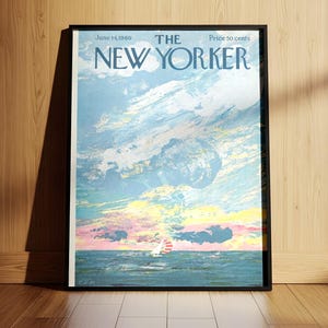 May include: Framed New Yorker magazine cover from June 14, 1982, featuring a seascape with a sailboat under a cloudy sky. The artwork is in shades of blue, pink, and yellow. The magazine is displayed on a wooden floor and leaning against a wooden wall.