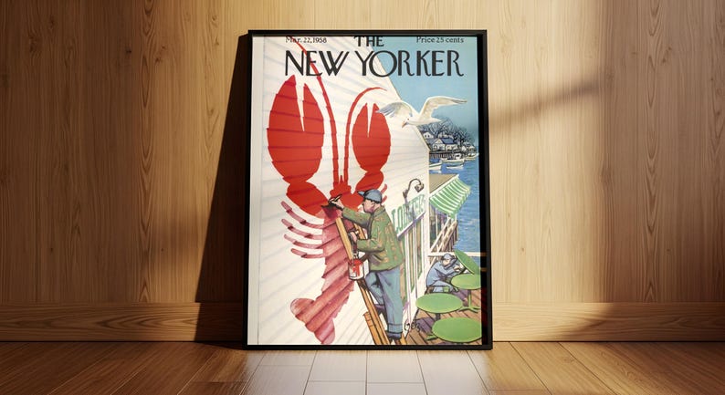 May include: Framed vintage New Yorker cover art with a large red lobster illustration. The cover art includes a man painting the lobster, a seagull, and the magazine's title. The frame is black and the artwork is leaning against a wooden wall.