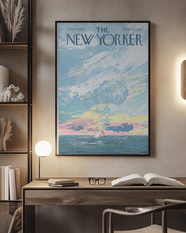 May include: A framed New Yorker magazine cover from June 14, 1969, featuring a seascape with a sailboat under a colorful sky. The artwork has a vintage aesthetic, with a black frame and the magazine's title at the top.