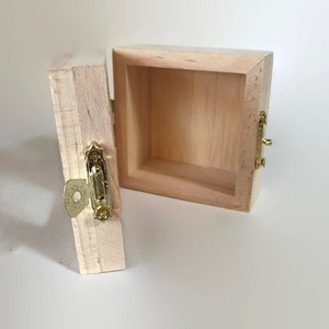 May include: A small wooden box with a hinged lid and a brass latch. The box is open and the inside is empty.